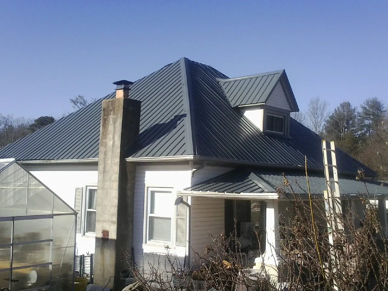 Dark blue standing seam metal roof on a white farmhouse with dormer — Slate & Tile Roof Repair by Roofing Brothers in El Mirage