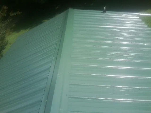 New green metal panels meeting at the ridge of a roof — Flat Roof Repair work by our crew in El Mirage