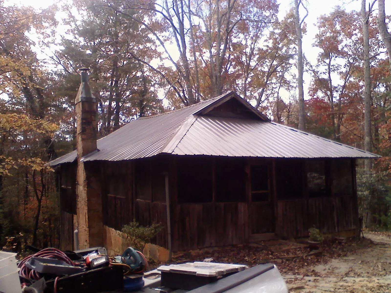 Brown metal hip roof on an old cabin with a stone chimney in El Mirage