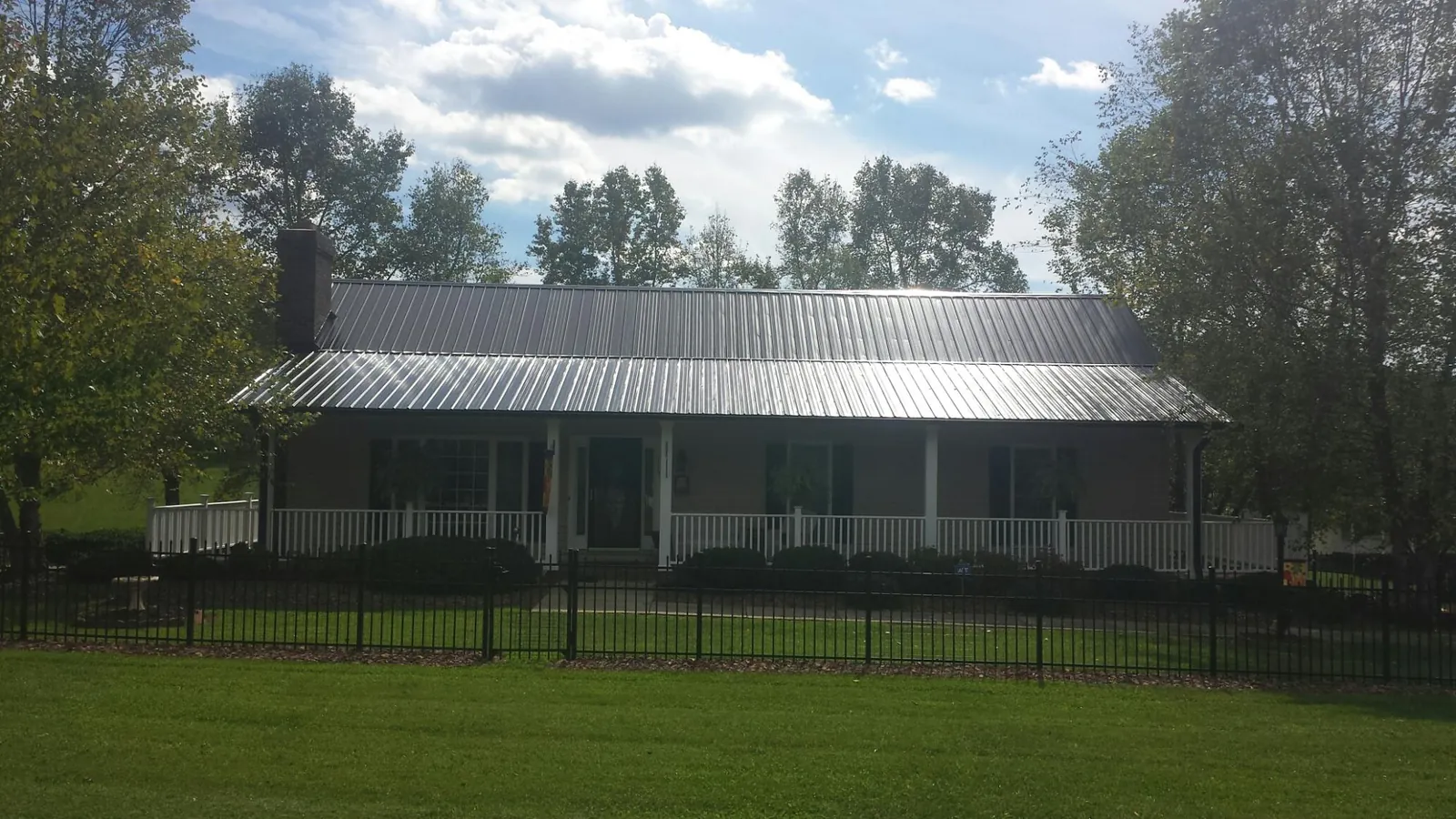 Gray metal roof on a brick ranch with a full width front porch — Gutter Guard Installation work by our crew in El Mirage